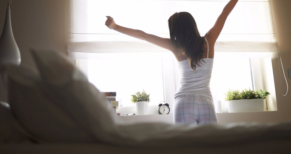 woman standing next to bed stretching