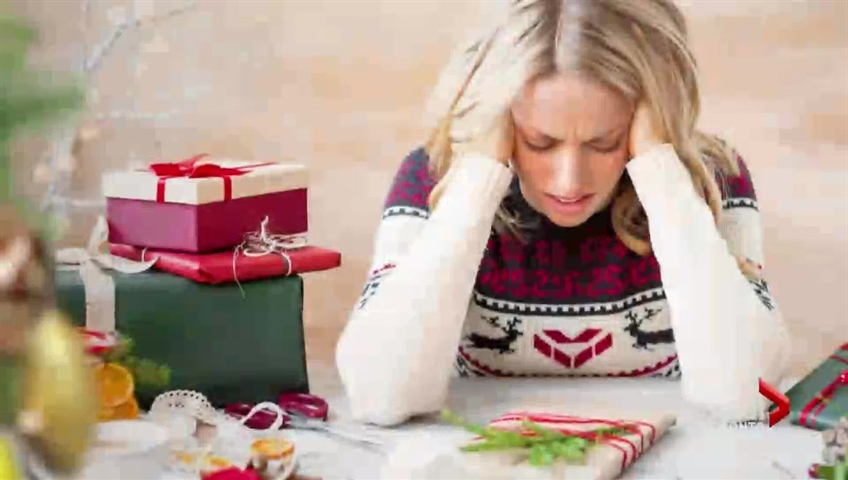 stressed out woman in a christmas sweater next to packages