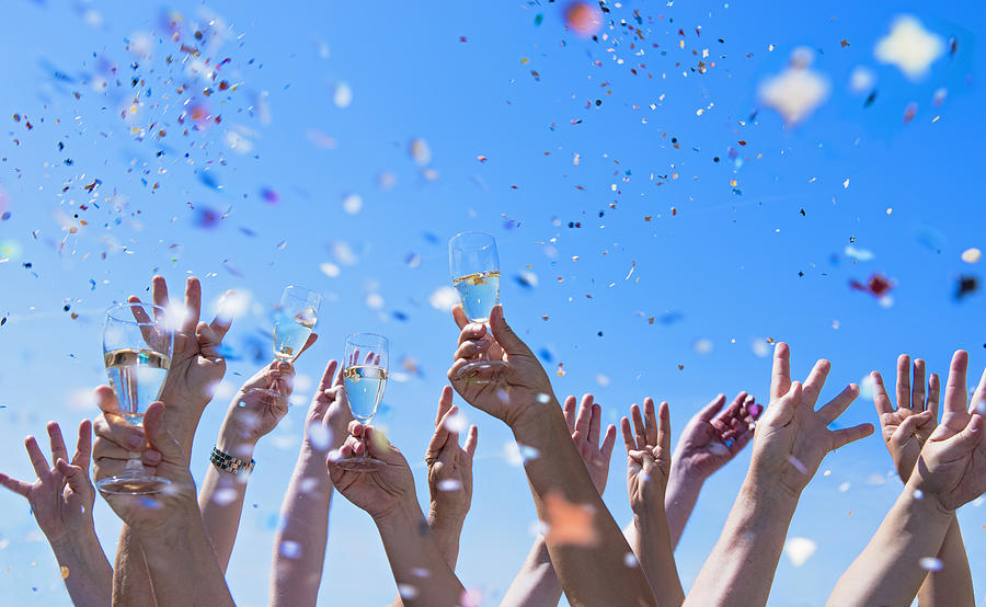 confetti and hands holding champagne glasses